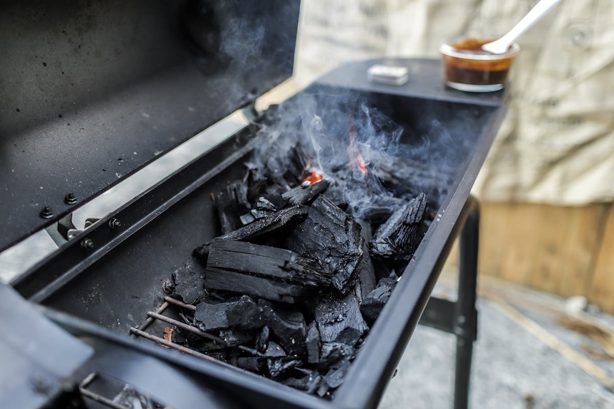 Glowing coals inside a grill at night, the warm red embers of a low and slow overnight brisket cook